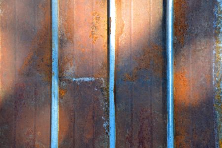 Image of a rusted corrugated metal privacy fence