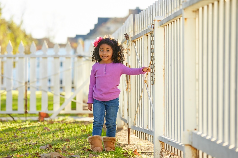 toddler standing next to fence